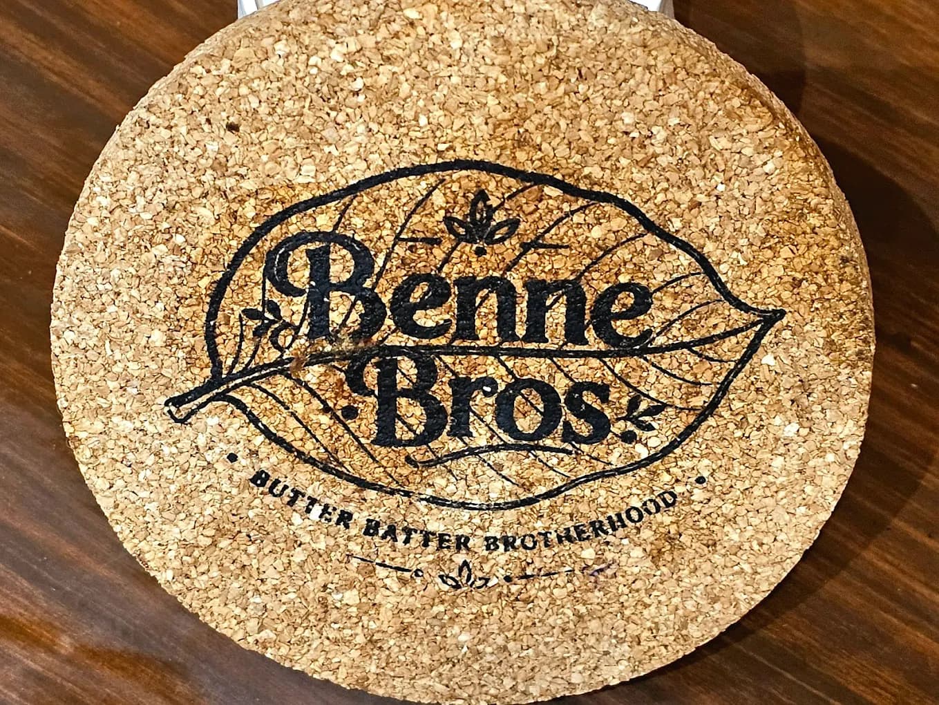 Benne Bros branded cork coaster on a wooden table