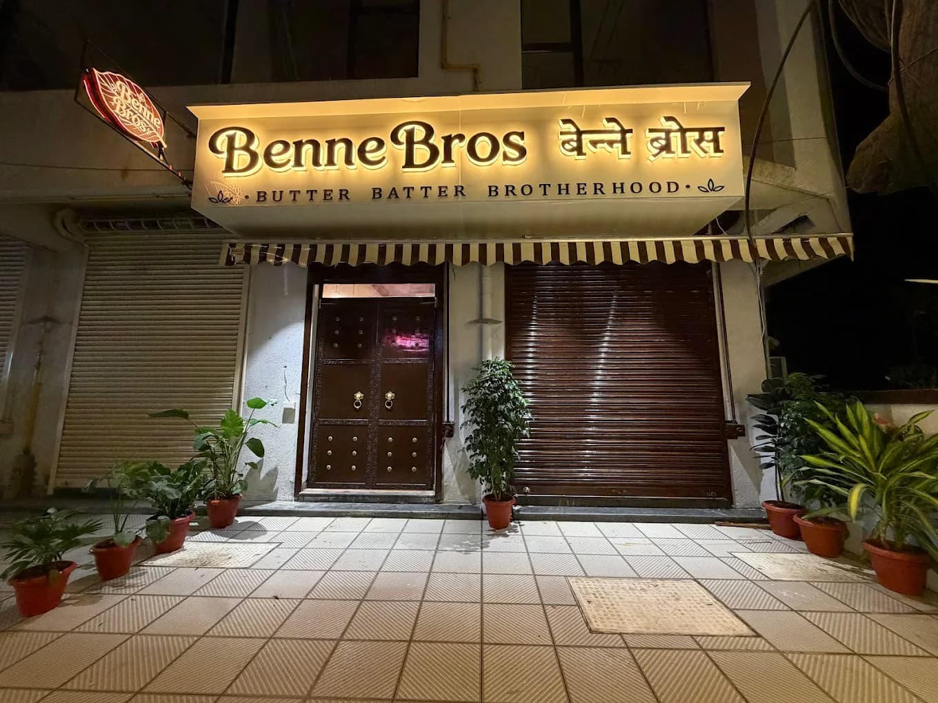 Benne Bros storefront lit up at night, with the Butter Batter Brotherhood signage glowing above the door